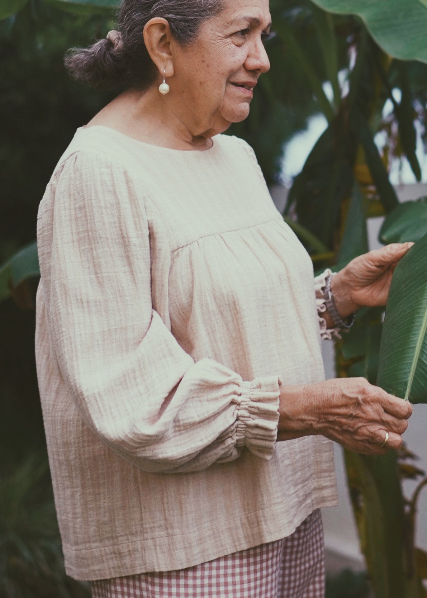 Woman wearing a light brown striped blouse with checkered pants outdoors