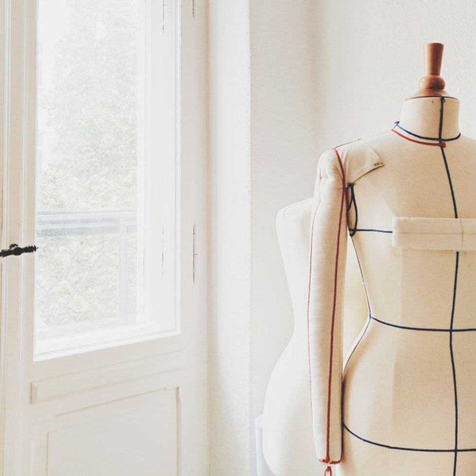 Detail of Slow Fashion Brand studio. Two dress forms mannequins next to a window.