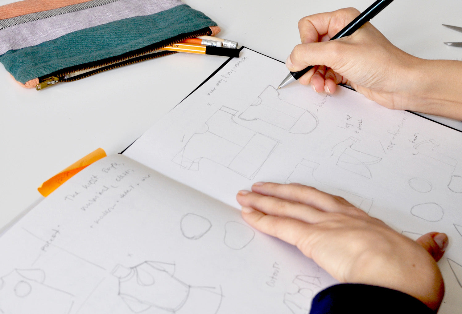 Close up of a sketchbook with drawings and handwritten notes. 